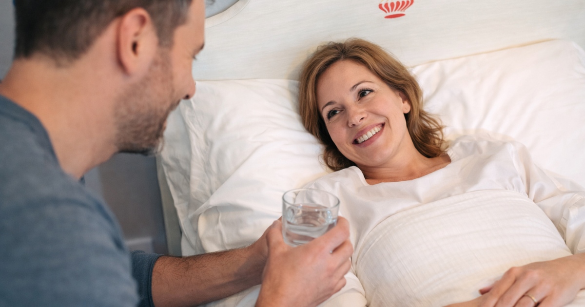 Family member helping a recovering patient with a pillow and glass of water